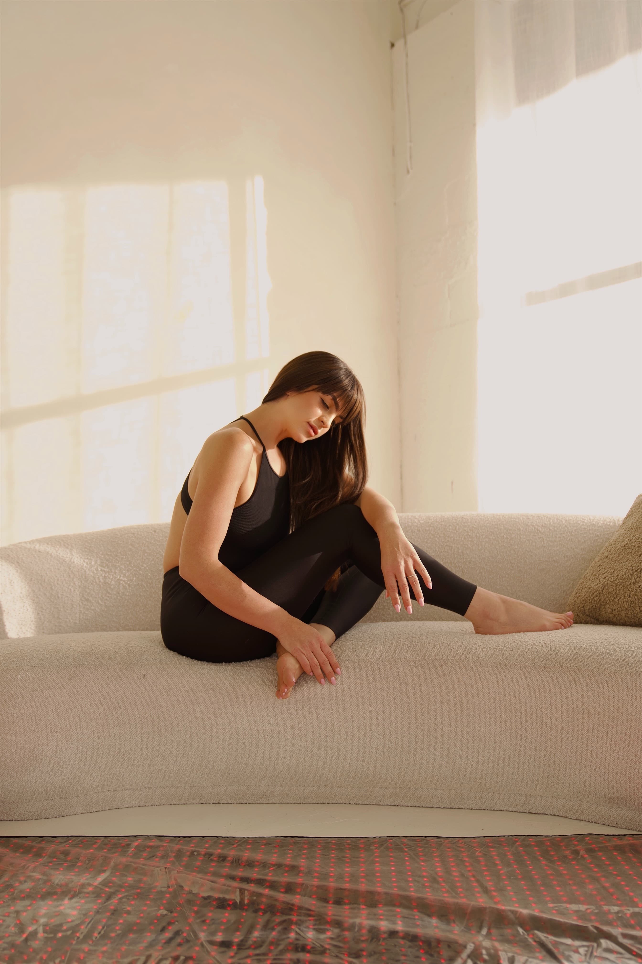 Woman resting on a cream sofa in soft afternoon light