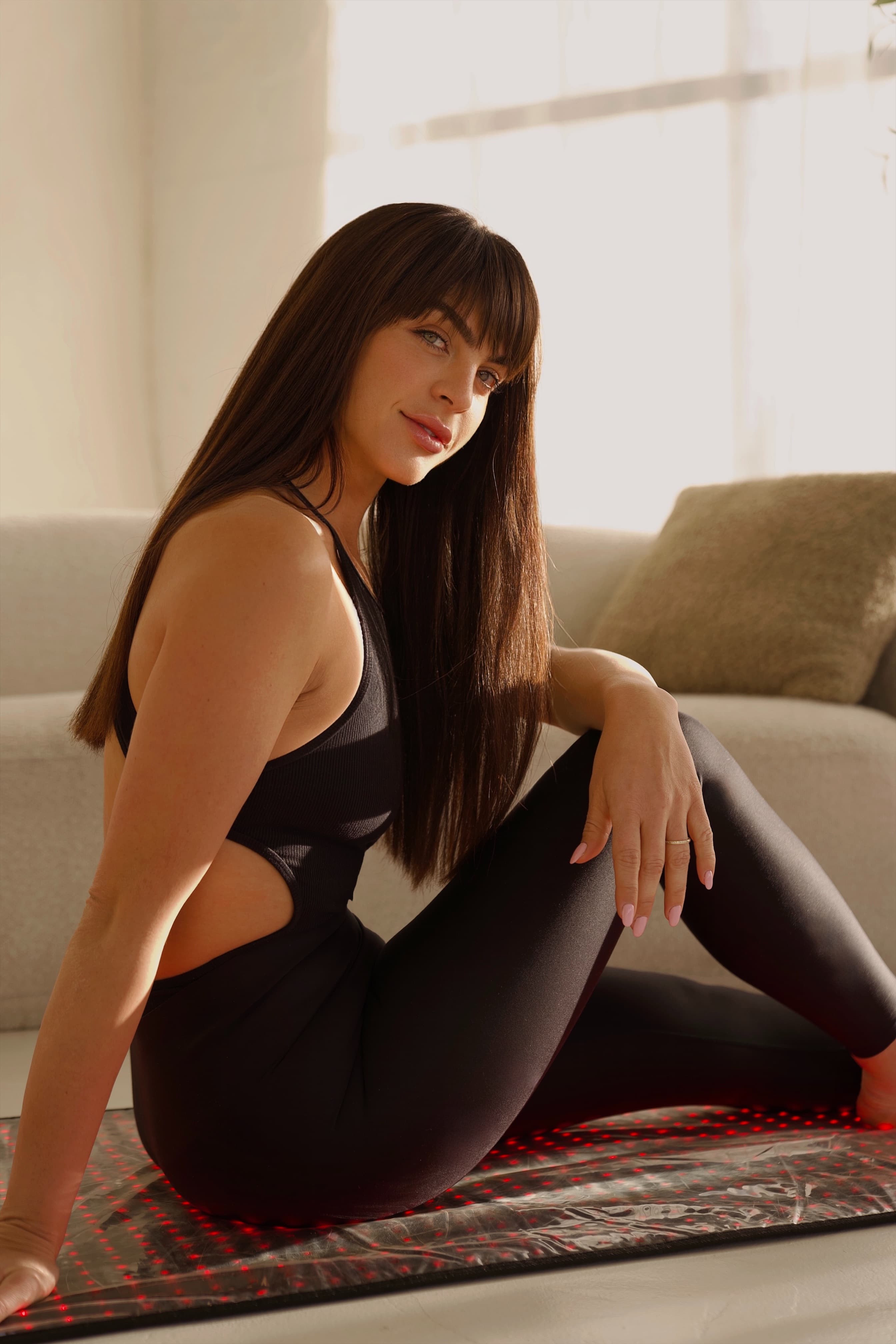 Founder seated on a treatment mat in a warm, light-filled studio